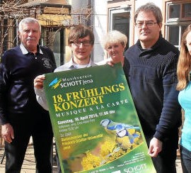 Fünf Personen halten Konzertplakat für die Konzerte mit dem Schott Blasorchester in die Kamera